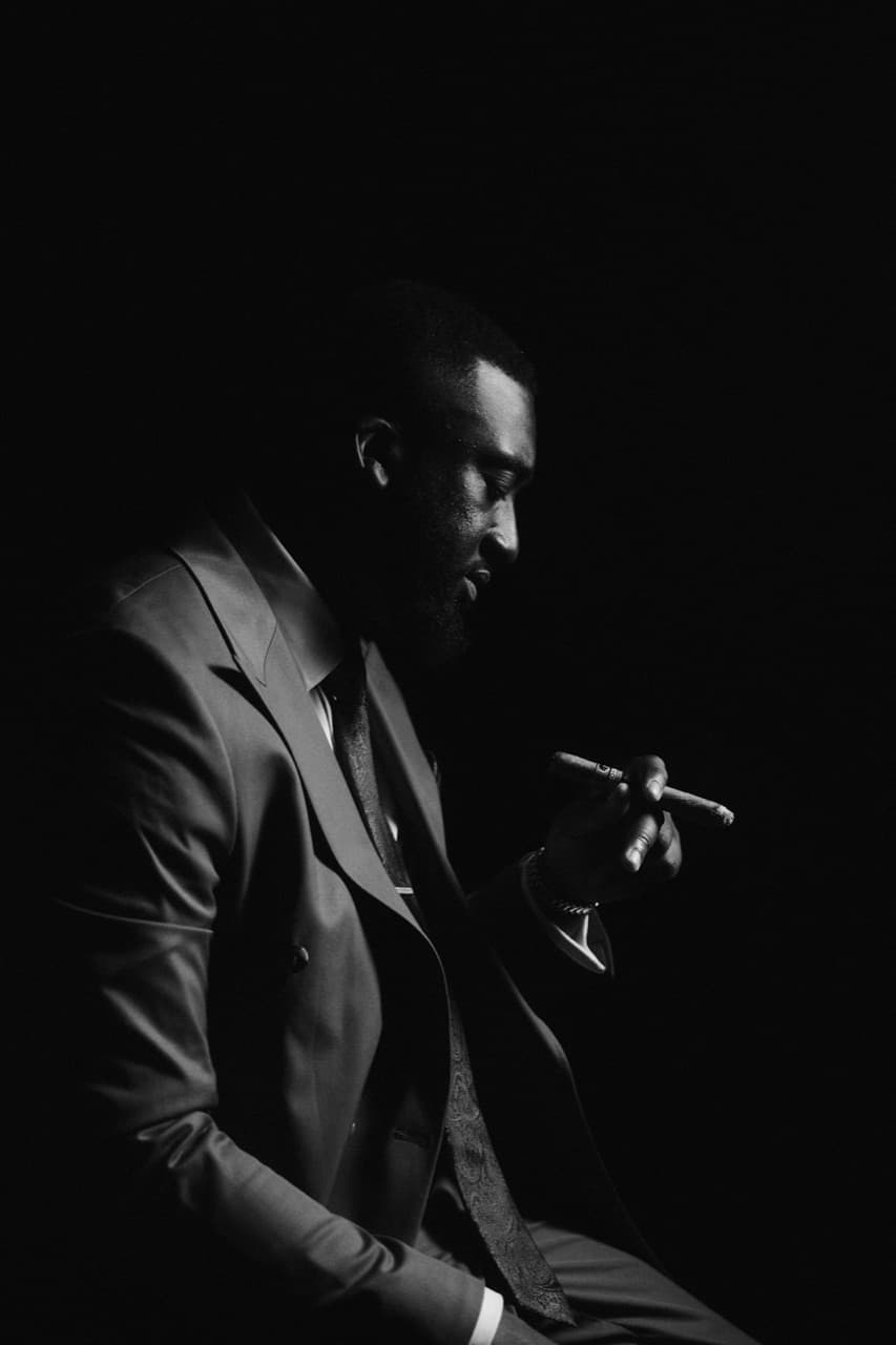 A client in a tailored double-breasted suit, seated with a cigar